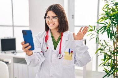 Çevrimiçi randevuda çalışan genç İspanyol doktor. Olumlu ve mutlu görünüyor. Kendine güvenen bir gülümsemeyle dişlerini gösteriyor. 
