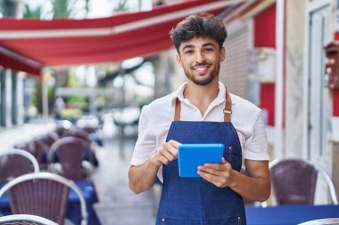 Young arab man waiter using touchpad working at restaurant