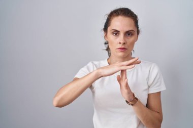 Güzel esmer kadın izole edilmiş arka planda duruyor. Elleriyle jest yapıyor, hayal kırıklığına uğramış ve ciddi bir yüz ifadesi var. 