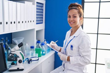 Young woman scientist writing on document working at laboratory