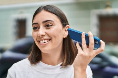 Genç İspanyol kadın gülümsüyor. Caddedeki akıllı telefondan kendine güvenen sesli mesaj dinliyor.