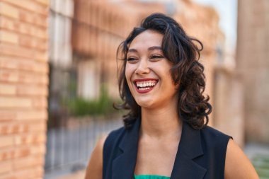 Young beautiful hispanic woman smiling confident looking to the side at street