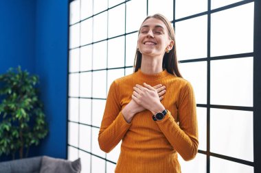 Elleri yüreğinin üstünde duran beyaz bir kadın.