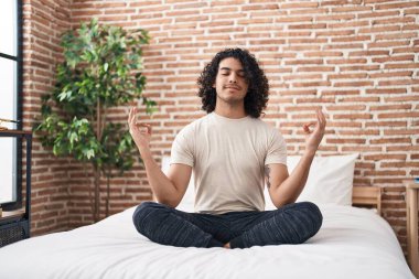 Yatak odasında, yoga egzersizi yapan genç latin adam.