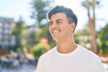 Young hispanic man smiling confident looking to the side at street