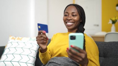 Afrikalı kadın evde akıllı telefonuyla online alışveriş yapıyor.