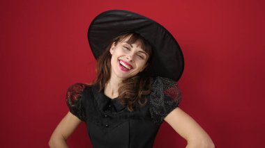 Young caucasian woman smiling wearing witch costume over isolated red background