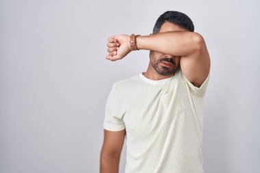 Sakallı İspanyol bir adam soyutlanmış arka planda duruyor, gözleri kollarıyla kapıyor, ciddi ve üzgün görünüyor. Görme, saklama ve reddetme konsepti 