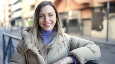 Sokakta kendine güvenen genç sarışın kadın gülümsüyor