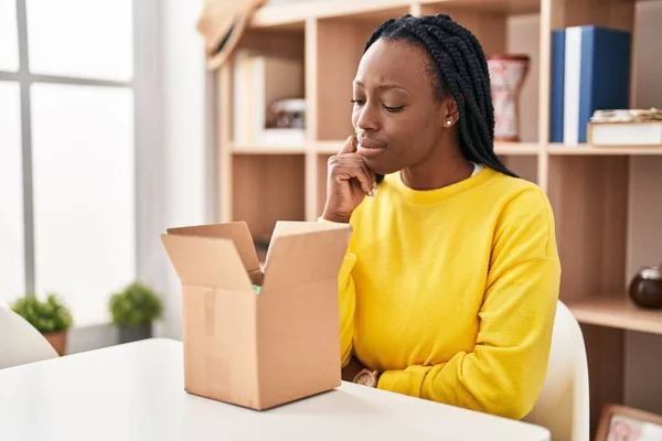 Beautiful Black Woman Opening Cardboard Box Thinking Concentrated Doubt Finger — Stock Photo, Image