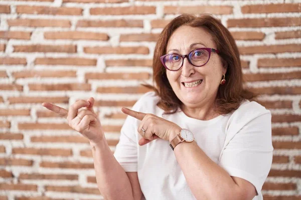 Mujer Mayor Con Gafas Pie Sobre Pared Ladrillos Sonriendo Mirando —  Fotos de Stock