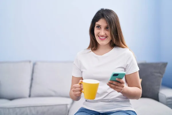 Genç Spanyol Kadın Kahve Içiyor Evde Akıllı Telefon Kullanıyor — Stok fotoğraf