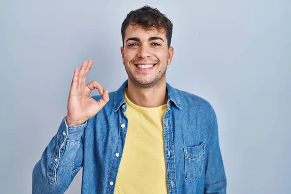 Homem Hispânico Jovem Sobre Fundo Azul Sorrindo Positivo Fazendo Sinal — Fotografia de Stock