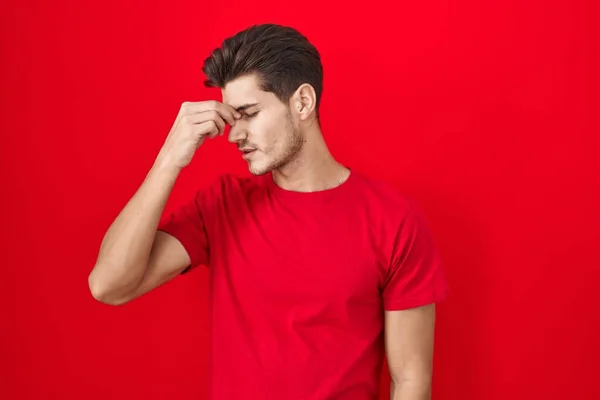 Mladý Hispánec Stojící Nad Červeným Pozadím Unaveně Mnul Nos Oči — Stock fotografie