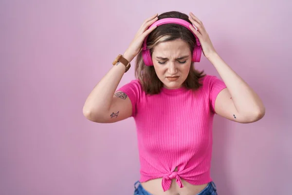 因为疼痛和偏头痛 金发女人在用耳机听音乐时感到头疼 绝望和紧张 手放在头上 — 图库照片