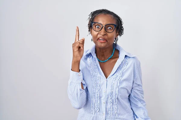 Африканская Женщина Дредами Стоит Белом Фоне Очках Показывая Пальцем Вверх — стоковое фото