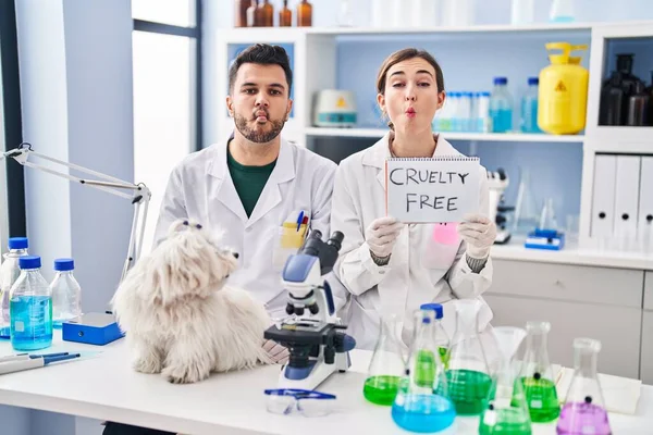 Stock image Young hispanic people working at scientist laboratory with dog making fish face with mouth and squinting eyes, crazy and comical. 