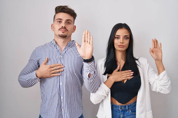 Unga Latinamerikanska Par Står Över Vit Bakgrund Svär Med Handen — Stockfoto