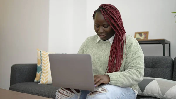 Afrykanka Plecionymi Włosami Pomocą Laptopa Siedzi Kanapie Domu — Zdjęcie stockowe