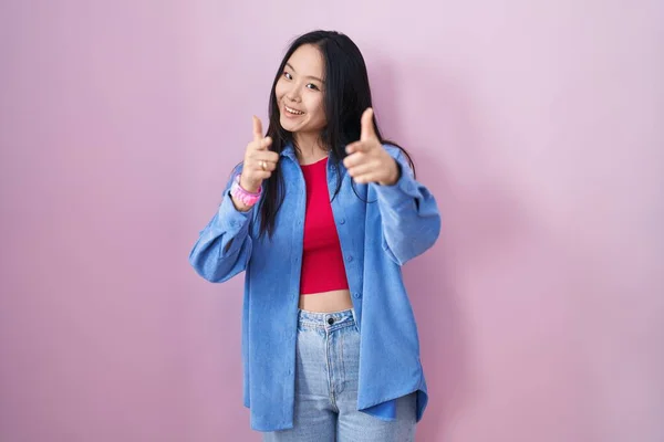 Mladá Asijská Žena Stojící Nad Růžovým Pozadím Ukazuje Prsty Fotoaparát — Stock fotografie