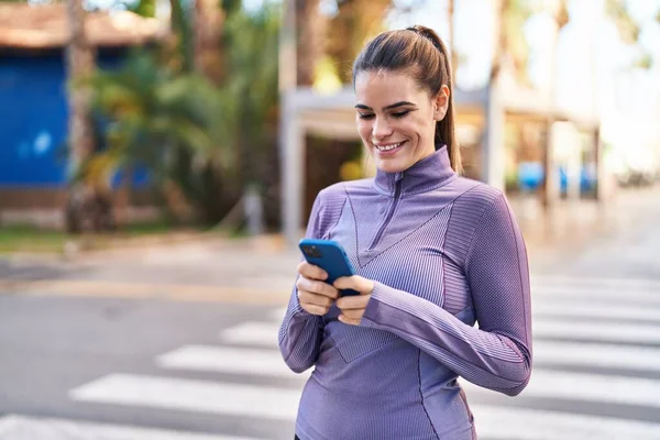 年轻美丽的惊慌失措的女人穿着运动服 在街上用智能手机 — 图库照片