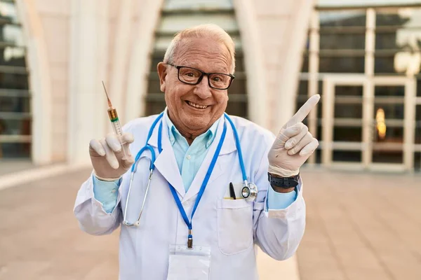 Старший Лікар Сірим Волоссям Тримає Шприц Посміхаючись Щасливим Вказуючи Рукою — стокове фото