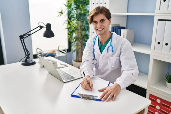 Young Caucasian Man Doctor Smiling Confident Writing Medical Report Clinic — Stock Photo, Image
