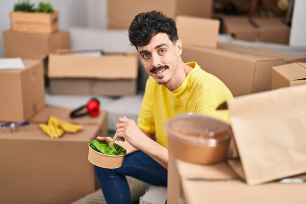 Young Caucasian Man Eating Salad Sitting Sofa New Home — Stock fotografie
