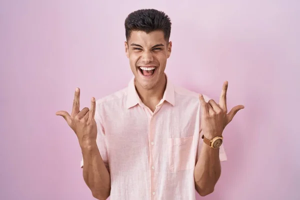Молодой Латиноамериканец Стоящий Розовом Фоне Кричащий Сумасшедшим Выражением Изображая Рок — стоковое фото