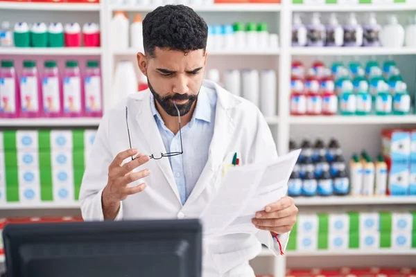 Young Arab Man Pharmacist Reading Document Doubt Expression Pharmacy — 스톡 사진
