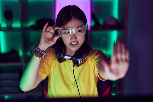 stock image Chinese woman streamer using computer and virtual reality glasses at gaming room