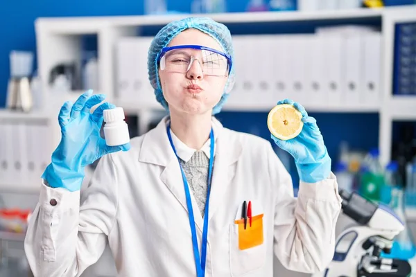 科学研究所で働く美しい女性は 薬とレモンの頬を面白い顔でパフしています 空気を吸い込み空気を吸い込み — ストック写真