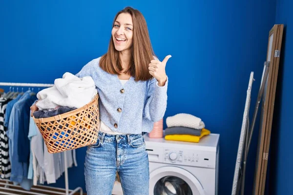 Junge Frau Hält Wäschekorb Und Lächelt Glücklich Und Positiv Daumen — Stockfoto