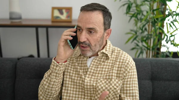 Mężczyzna Średnim Wieku Kłóci Się Przez Smartfona Siedzi Kanapie Domu — Zdjęcie stockowe