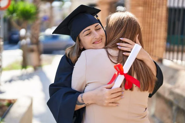 母親と娘が大学で卒業を祝うのを抱き合って — ストック写真