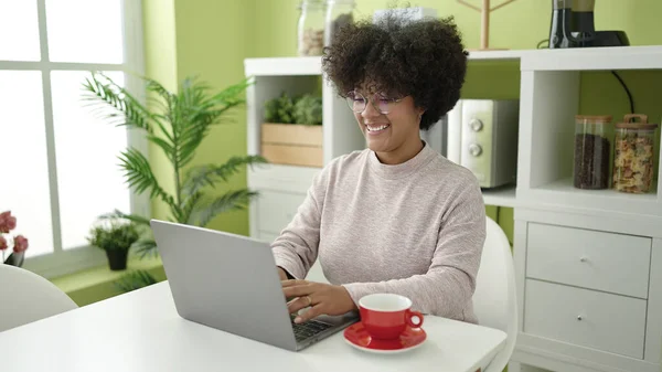 使用笔记本电脑的年轻非洲裔美国妇女坐在家里的桌子上 — 图库照片