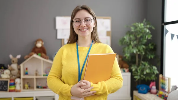 Young Blonde Woman Preschool Teacher Smiling Confident Holding Books Kindergarten — ストック写真