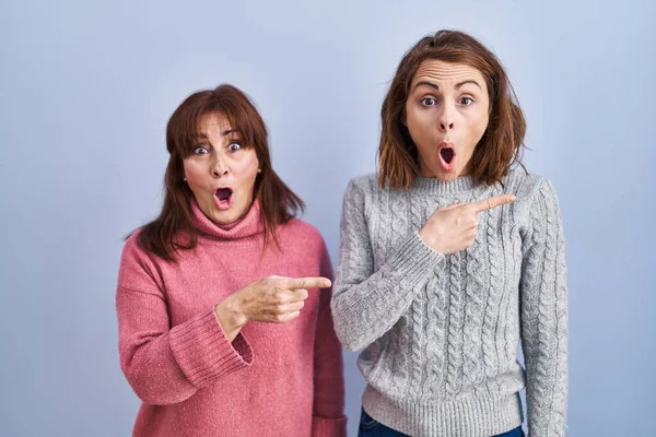 Mother Daughter Standing Blue Background Surprised Pointing Finger Side Open — Stock Photo, Image