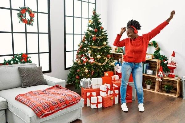 アフリカ系アメリカ人女性は音楽を聴きながら家でクリスマスツリーのそばで踊る — ストック写真