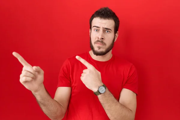 Joven Hombre Hispano Vistiendo Casual Camiseta Roja Señalando Lado Preocupado — Foto de Stock