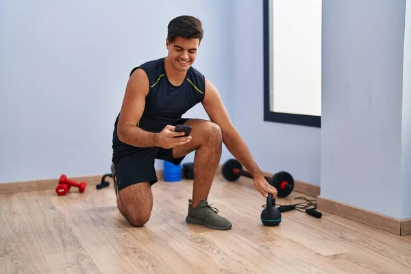 Jovem Hispânico Usando Kettlebell Treinamento Smartphones Centro Esportivo — Fotografia de Stock