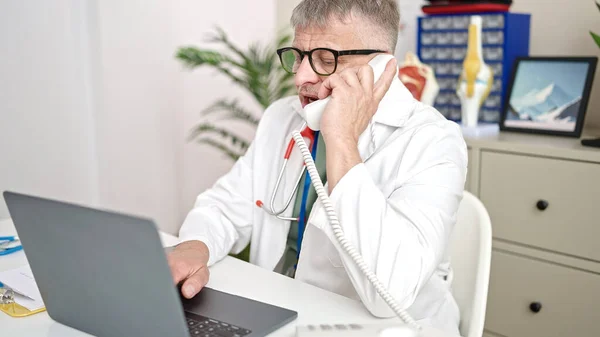 Середнього Віку Сіроволоса Людина Лікар Використовує Ноутбук Розмовляє Телефону Клініці — стокове фото