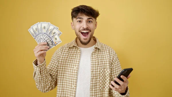 Young Arab Man Using Smartphone Holding Dollars Isolated Yellow Background — Stock Photo, Image