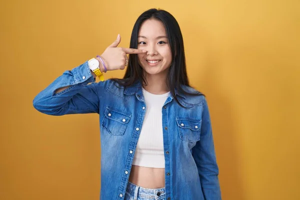 Молодая Азиатка Стоящая Жёлтом Фоне Указывая Пальцем Лицо Нос Весело — стоковое фото