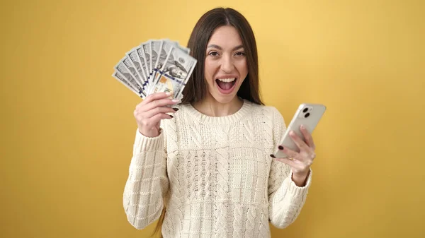 Młoda Piękna Latynoska Kobieta Pomocą Smartfona Gospodarstwa Dolarów Odizolowanym Żółtym — Zdjęcie stockowe