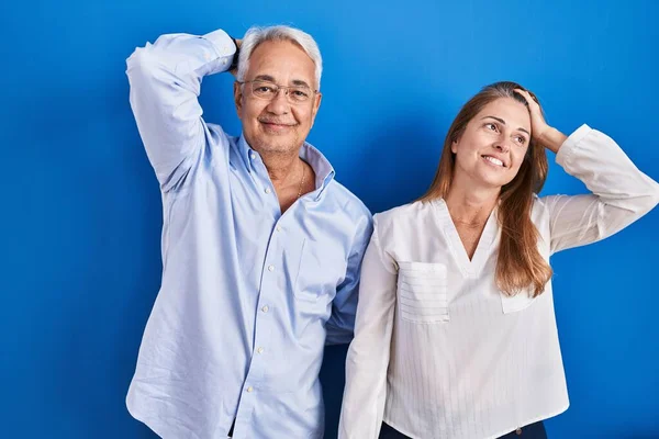 Middelbare Leeftijd Hispanic Paar Staan Blauwe Achtergrond Glimlachen Zelfverzekerd Aanraken — Stockfoto