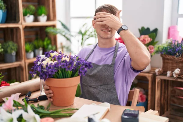 花屋で働く白人ブロンドの男は笑顔で 驚きのために目を覆う顔で手で笑っています 視覚障害の概念 — ストック写真
