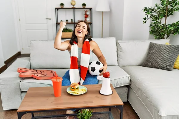 支持足球队的年轻漂亮的惊慌失措的女人坐在家里的沙发上 — 图库照片