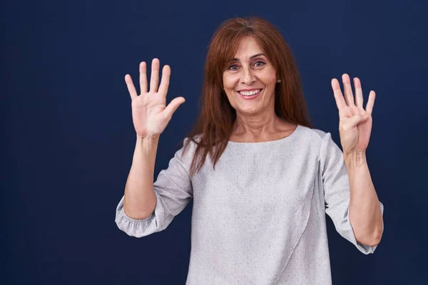 Женщина Средних Лет Стоит Синем Фоне Показывая Показывая Пальцами Номер — стоковое фото