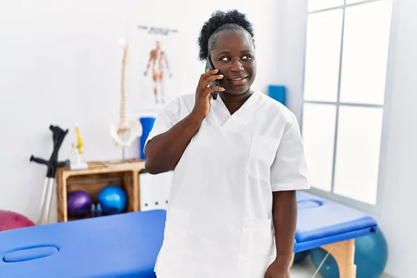Young African American Woman Wearing Physiotherapist Uniform Talking Smartphone Clinic — Stockfoto